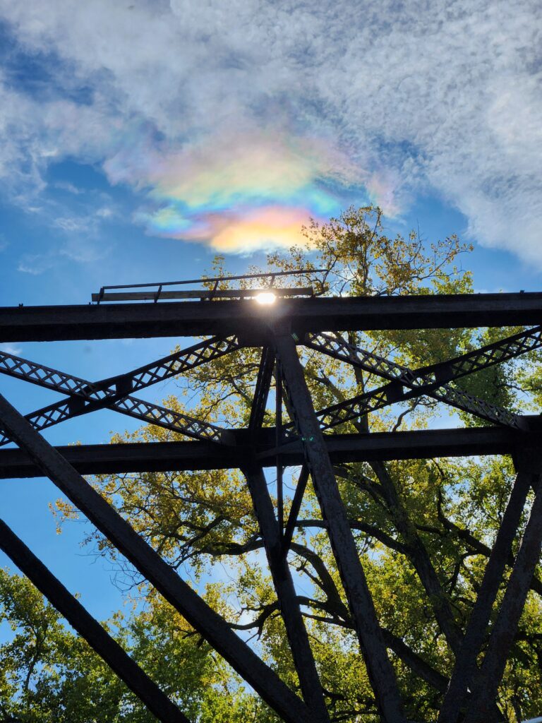 Picture of the top of a bridge in Minneapolis, with two partial rainbows in the sky.